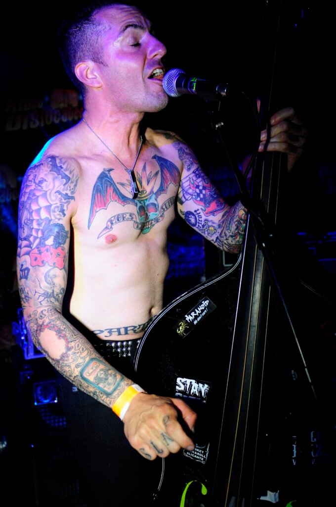 Sångaren i Koffin Kats. snaggat hår, tatueringar, kontrabas och bar överkropp.