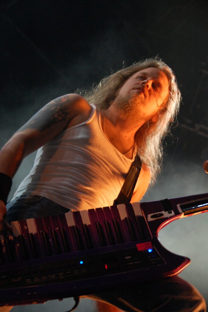 En keytarist med vitt linne och långt blont hår.