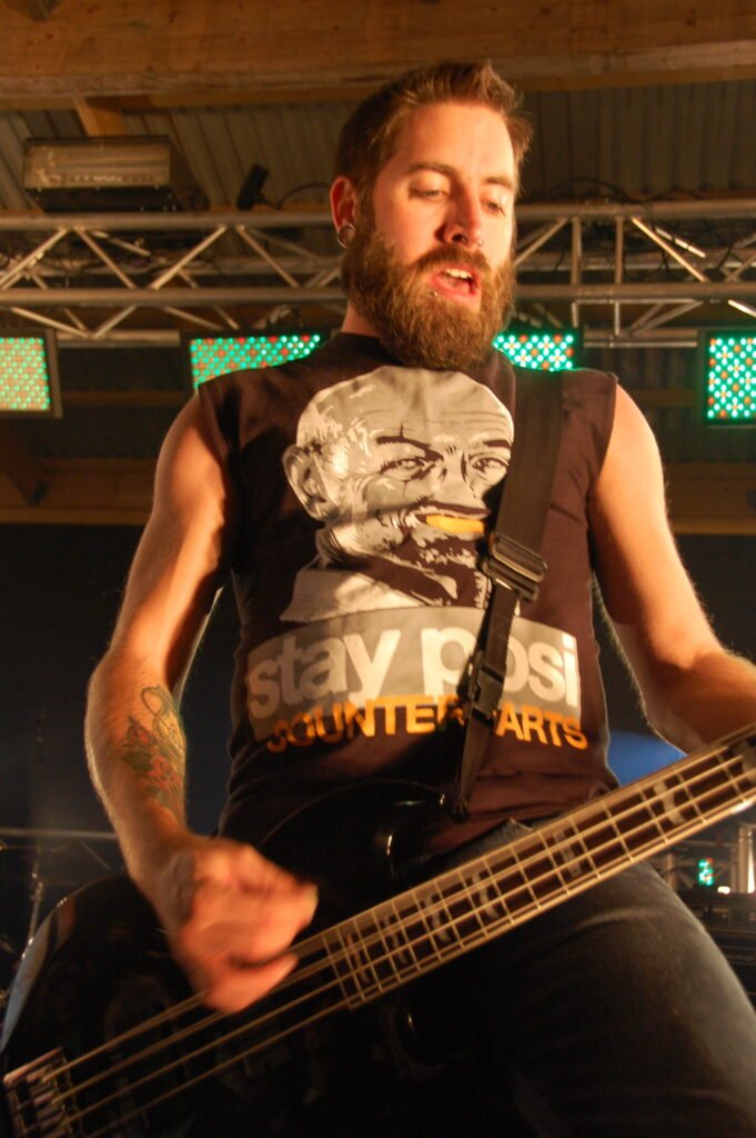 basist i svart t-shirt med tryck och kort hår och skägg.